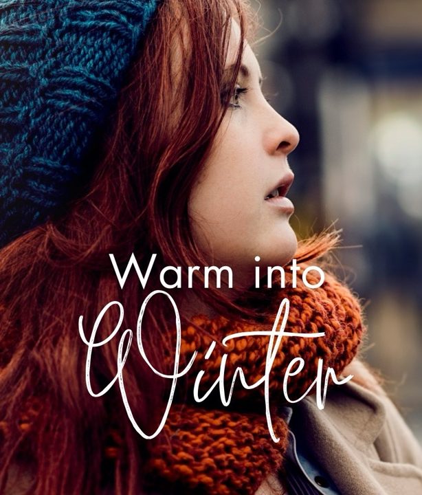 red headed woman wearing a blue beanie with text warm into winter.