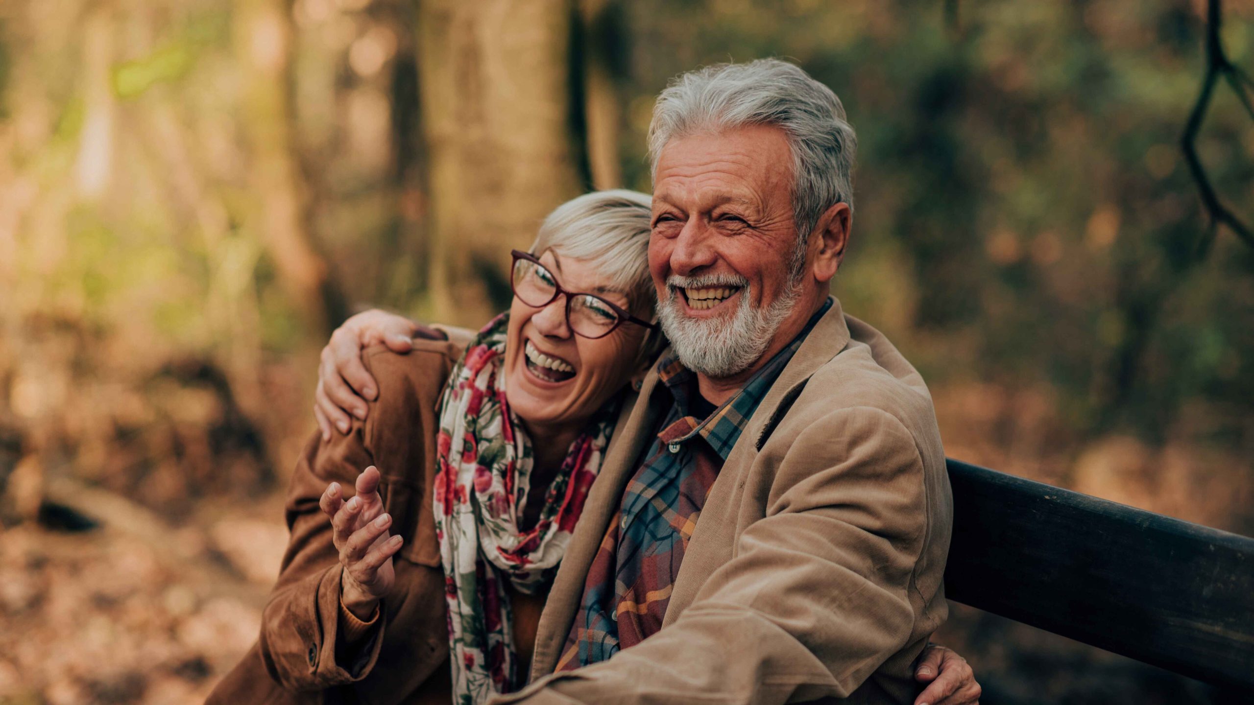 Couple loving each other on a bench in the woods.